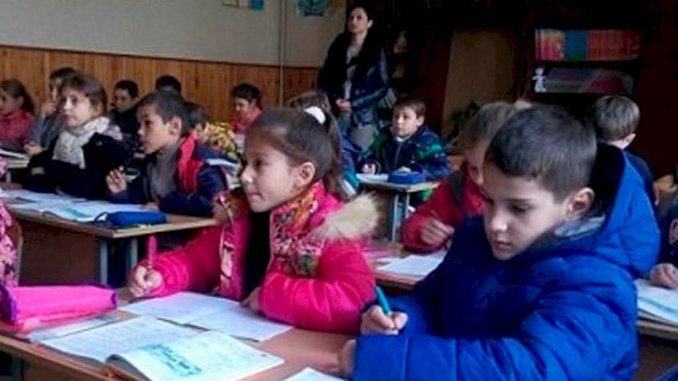    Soyuqdan sinifdə palto ilə oturan şagirdlər   